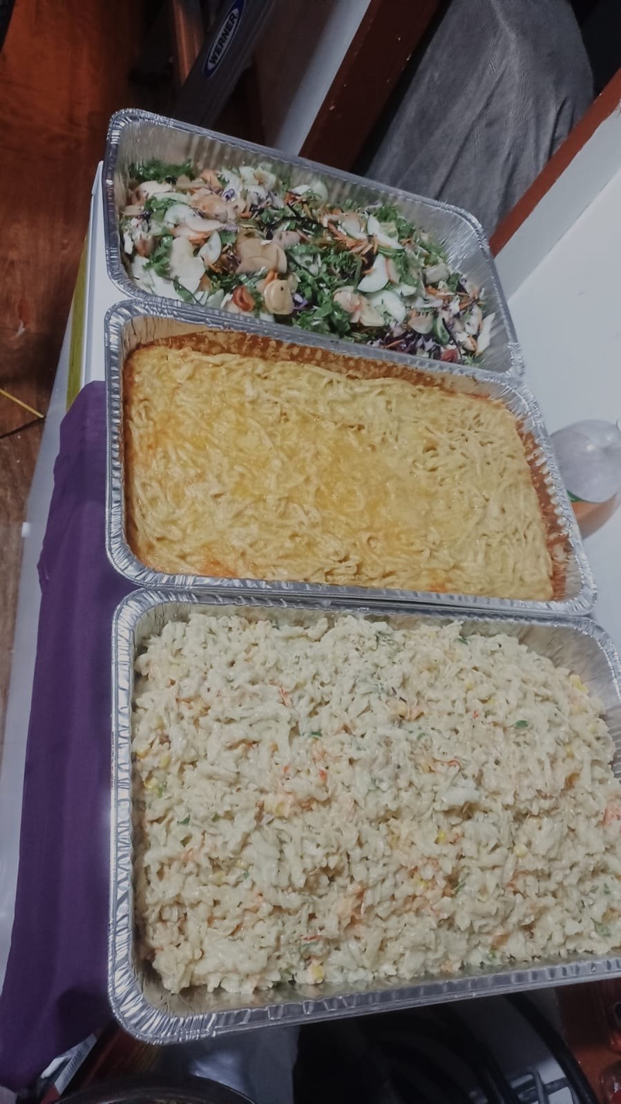 Three trays: salad, baked pasta and rice